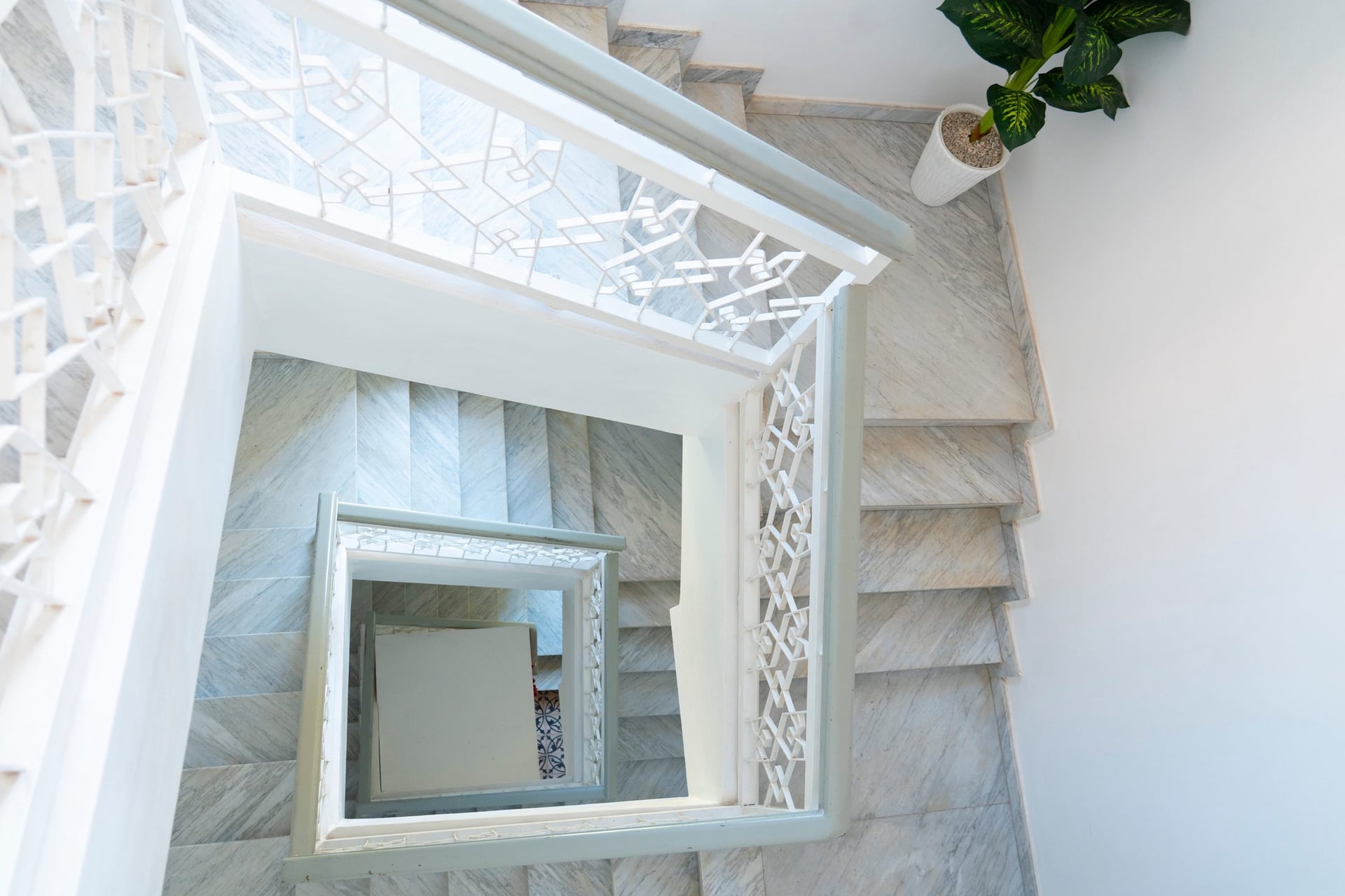 La cage d'escalier vue d'en haut, ses rambardes en fer forgé blanc